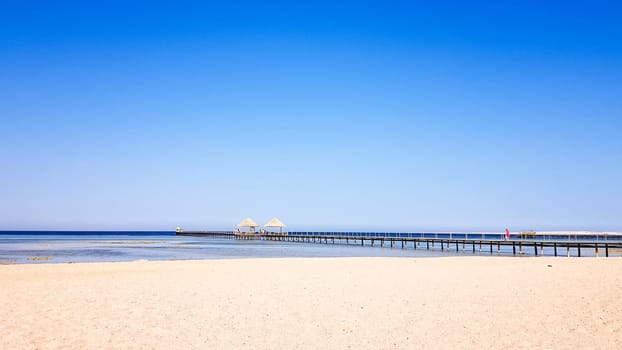 A beautiful sandy beach without people and a tropical blue sea with blue sky background