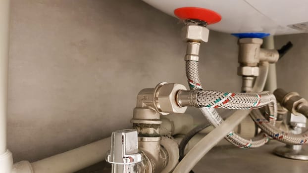 Connection of water supply, hot and cold water to the boiler. Hose for hot and cold water in the bathroom. Plumbing connections for a domestic electric water heater