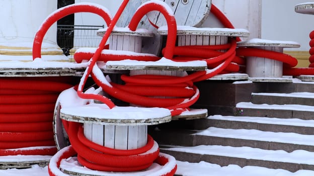 Large coils of red flexible corrugated pipe used to protect cables in electrical installations. Lots of colored polyethylene plastic hose used in construction for plumbing systems