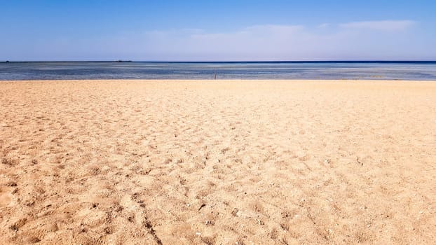 A beautiful sandy beach without people and a tropical blue sea with blue sky background