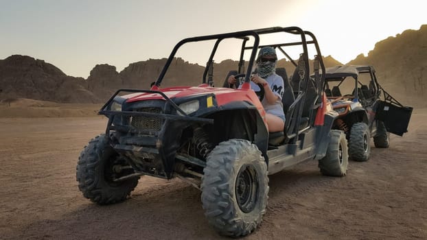 Egypt, Sharm El Sheikh - October 10, 2020. Active woman driving an ATV on a dirt road in the desert against the backdrop of rocky sandy mountains in the sunset