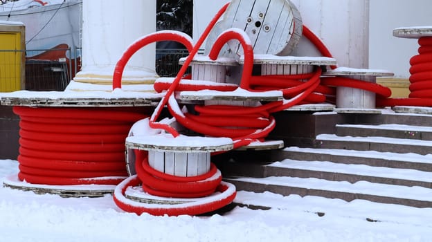Large coils of red flexible corrugated pipe used to protect cables in electrical installations. Lots of colored polyethylene plastic hose used in construction for plumbing systems