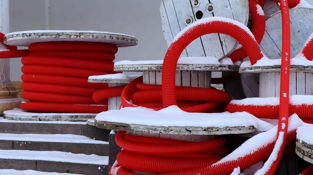 Large coils of red flexible corrugated pipe used to protect cables in electrical installations. Lots of colored polyethylene plastic hose used in construction for plumbing systems