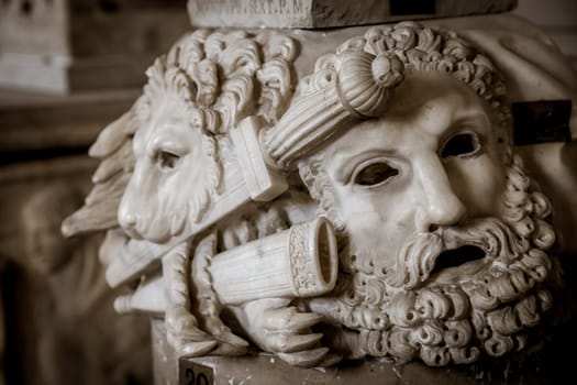 Ancient theatre mask, made of marble, located at the base of a Roman column in Rome - Italy