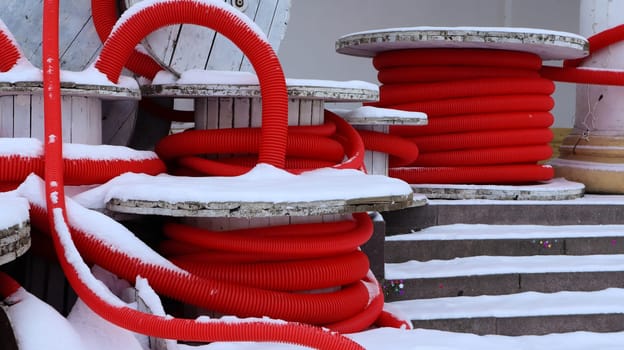 Large coils of red flexible corrugated pipe used to protect cables in electrical installations. Lots of colored polyethylene plastic hose used in construction for plumbing systems