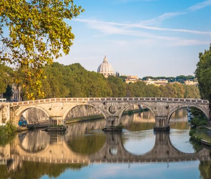 ROME, ITALY - CIRCA AUGUST 2020: Bridge on Tiber river with Vatican Basilica cupola in background and sunrise light.