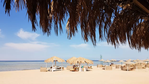 A beautiful tropical beach with thatched umbrellas on the shores of the Red Sea in Sharm El Sheikh. Summer landscape Beautiful sunny beach in Egypt. The concept of vacation, travel, vacation.