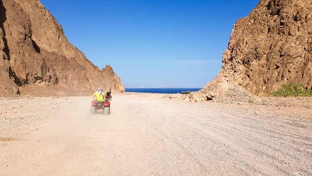 Desert in Egypt. Rocky sand hills. A lone tourist on an ATV in the desert against the background of blue sky and mountains is walking towards the Red Sea. Landscape in the desert