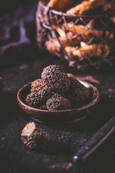 Black truffle in bowl on dark background, cooking delicacy