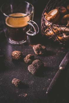 Black truffle on dark kitchen table with black coffee and mushrooms, cooking delicacy