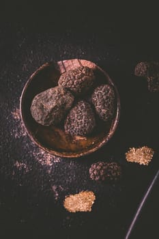 Black truffle in bowl on dark background, cooking delicacy