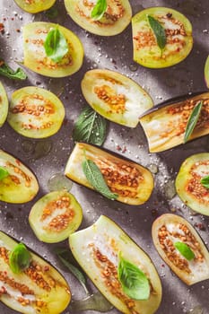 Small raw eggplants prepared for baking on baking sheet with herbs and spices