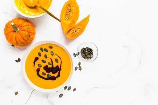 Homemade pumpkin soup with pumpkin oil and seeds on marble background