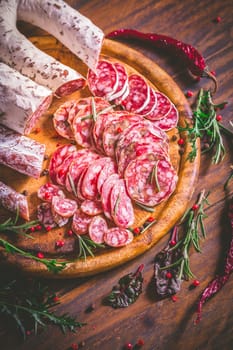 Charcuterie - Assortment of air-dried salami and sausage on wooden cutting board with spices