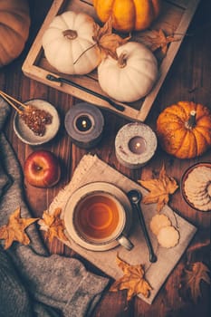 Hot tea with cookies, apple and fall foliage and pumpkins on wooden background