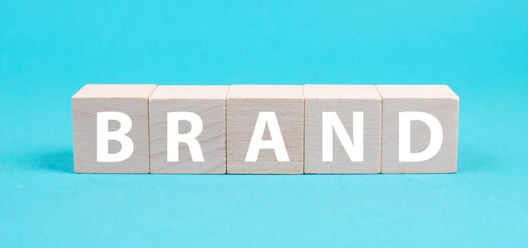 The word brand is standing on wooden cubes, positioning of a company, marketing, blue colored background