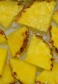 Close up view of the yellow pineapple slices in lemonade background. Texture of cooling sweet summer's drink with macro bubbles on the white background. Flat design. Vertical image.