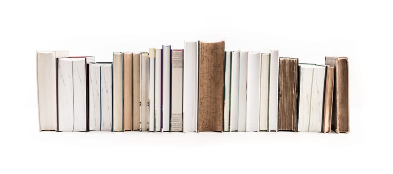 Assortment of new and old books in a row isolated on white background.
