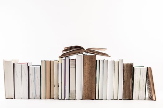 Assortment of new and old books in a row isolated on white background.