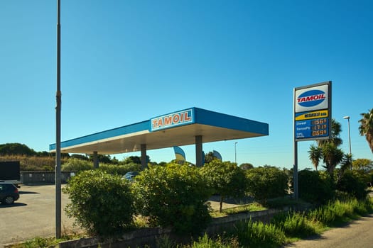 Civitavecchia. Italy - January 26, 2025: Modern Tamoil gas station in Civitavecchia, Italy, showcasing fuel prices and clean facilities under a clear blue sky. Concept: transportation, energy, and service.