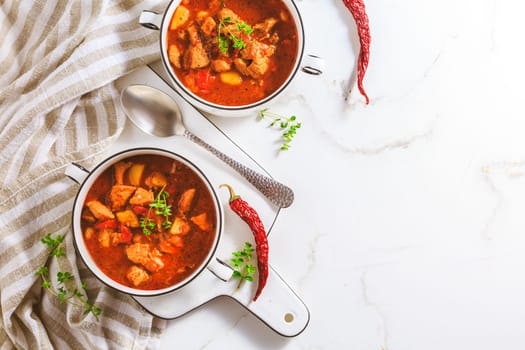 Beef goulash soup - hearty Hungarian soup of meat and vegetables seasoned with paprika on white background