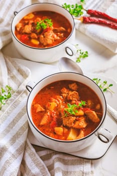 Beef goulash soup - hearty Hungarian soup of meat and vegetables seasoned with paprika on white background