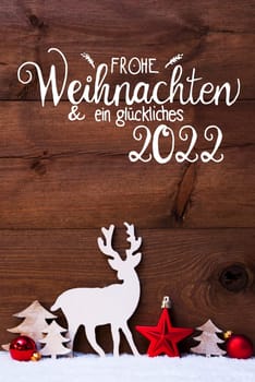 German Calligraphy Frohe Weihnachten Und Ein Glueckliches 2022 Means Merry Christmas And Happy 2022. Christmas Decoration With Tree, Deer And Red Ball. Brown Wooden Background