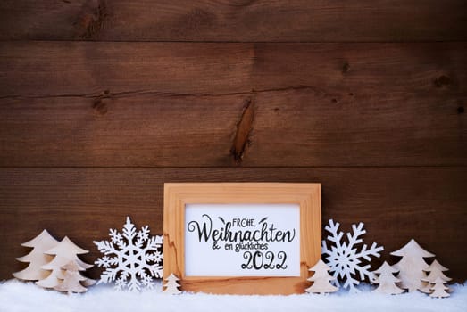German Calligraphy Frohe Weihnachten Und Ein Glueckliches 2022 Mean Merry Christmas And Happy 2022. White Christmas Ornament Like Snowflake And Tree. Wooden Background With Snow