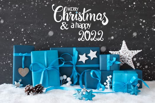 English Calligraphy Merry Christmas And A Happy 2022. Turquoise Gift With Bow And Christmas Decoration. Black Background With Snow And Snowflakes