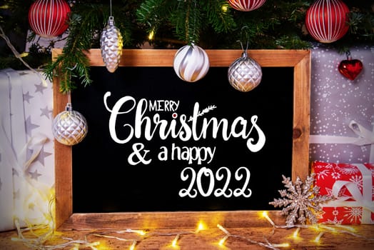 Blackboard With English Calligraphy Merry Christmas And Happy 2022. Christmas Tree With Ball, Gifts And Fairy Lights