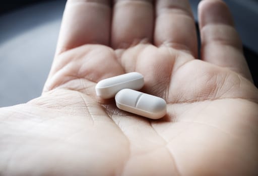 Close up of two pills in hand. Pharmaceutical medicaments.