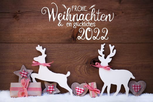 German Calligraphy Frohe Weihnachten Und Ein Glueckliches 2022 Mean Merry Christmas And Happy 2022. Wooden Christmas Ornament Like Present, Heart And Wooden Deer. Wooden Background With Snow