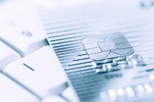 Closeup image of o credit card in silver and blue tone, selective focus, keyboard in background