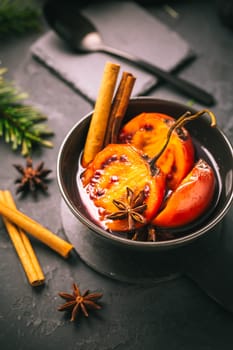 Christmas dessert - flamed tamarillo in hot wine punch with cinnamon and anise on black background