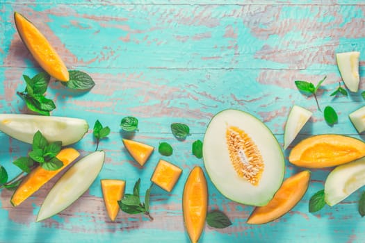 Healthy snack - Piel de sapo melon and cantaloupe with fresh mint on cyan wooden table