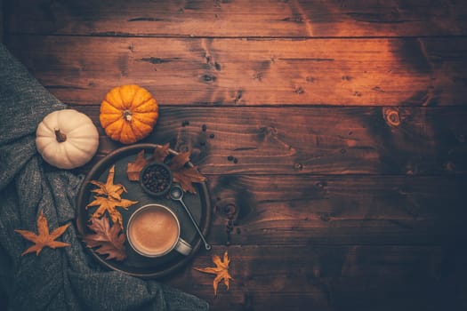 Autumn flatlay with cup of coffee, pumpkins and cuddle blanket on wooden background