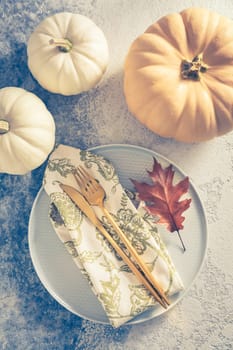 Place setting for Thanksgiving in vintage style with pumpkins and autumn leaf