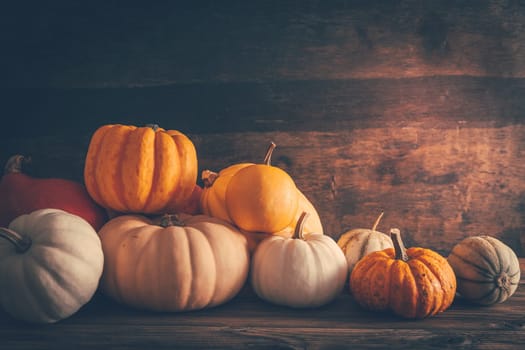 Happy thanksgiving - still life with different pumpkins and autumn leaves on wooden background