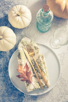 Place setting for Thanksgiving in vintage style with pumpkins and autumn leaf