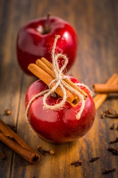 Organic red apples with cinnamon stick and cloves as baking ingredients on wooden background