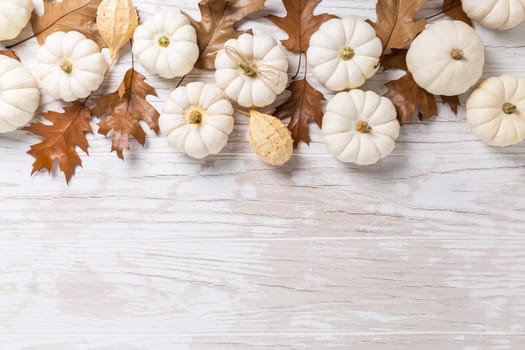 Happy thanksgiving - background with white pumpkins and autumn leaves on white wooden background