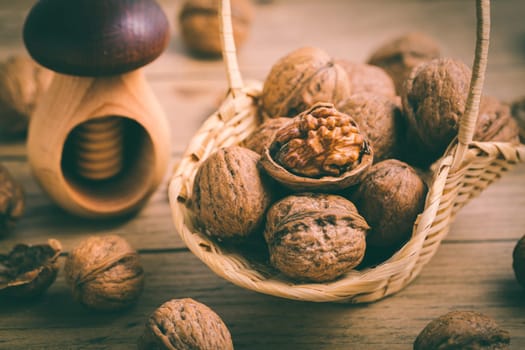 Organic walnuts with small nutcraker as baking ingredients on wooden background