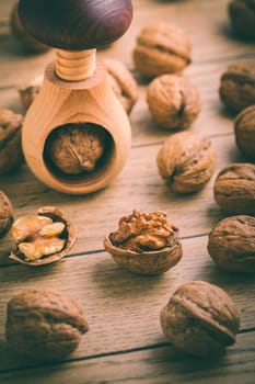 Organic walnuts with small nutcraker as baking ingredients on wooden background