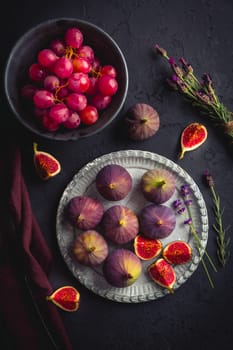 Organic fresh figs with red grapes and lavender on dark background