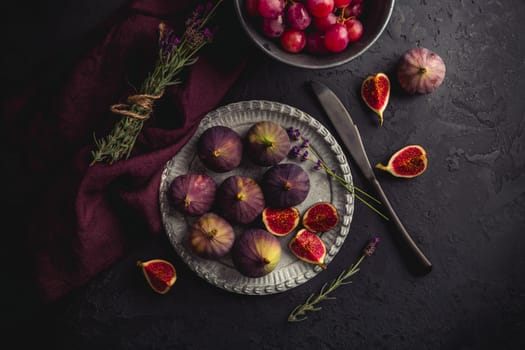 Organic fresh figs with red grapes and lavender on dark background