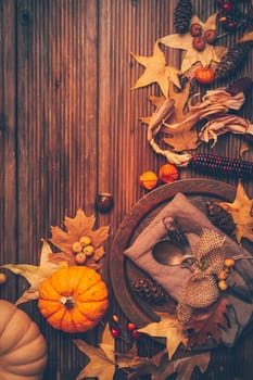 Autumn flat lay with plate setting, pumpkins and autumn leaves with copy space