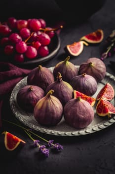 Organic fresh figs with red grapes and lavender on dark background