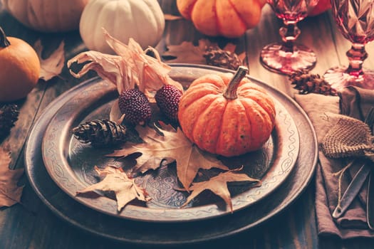 Place setting for Thanksgiving with pumpkins and autumn leaves in vintage style
