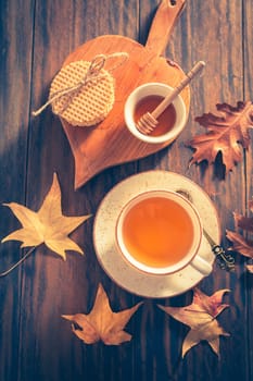 Hot tea with honey, homemade wafer biscuit and autumn leaves on wooden background