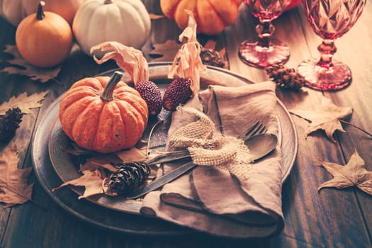 Place setting for Thanksgiving with pumpkins and autumn leaves in vintage style